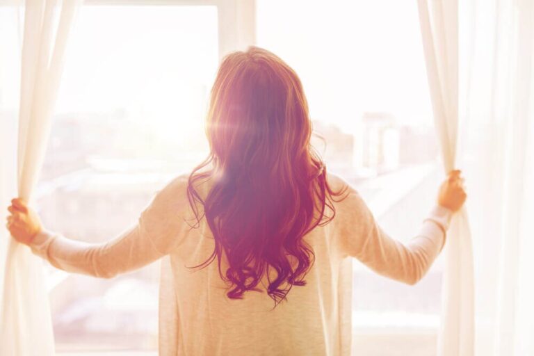 woman opening curtains in her home