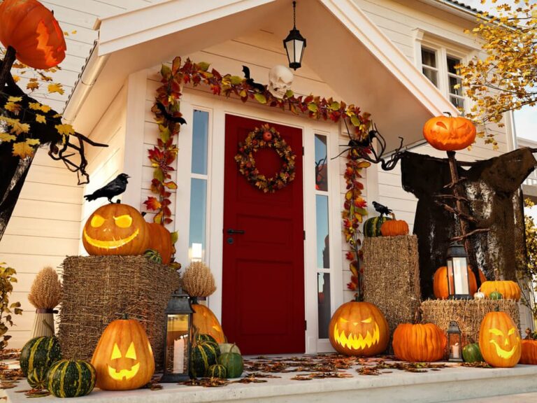 front of house decorated with pumpkins, leaves, and hay bales for halloween