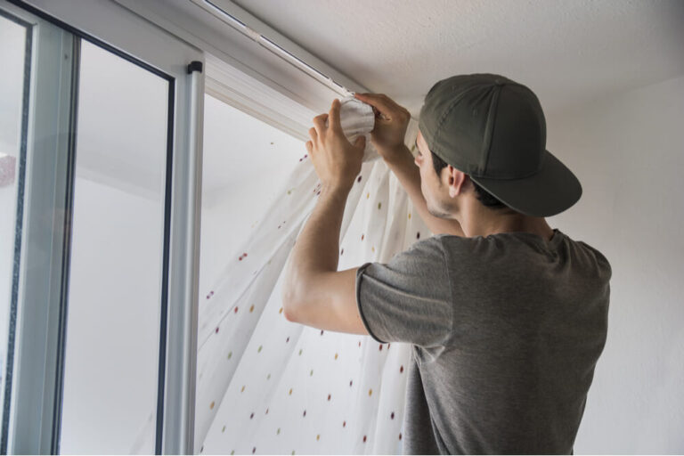 man hanging curtains in his apartment or home