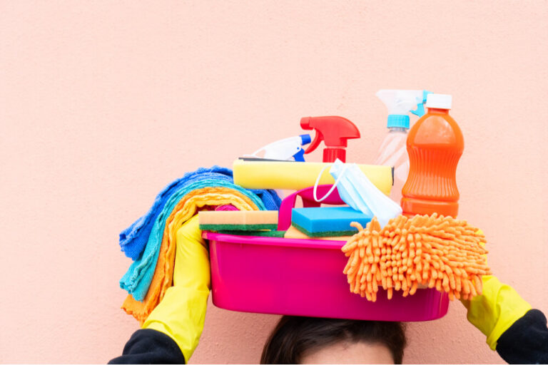 holding a bucket filled with cleaning supplies